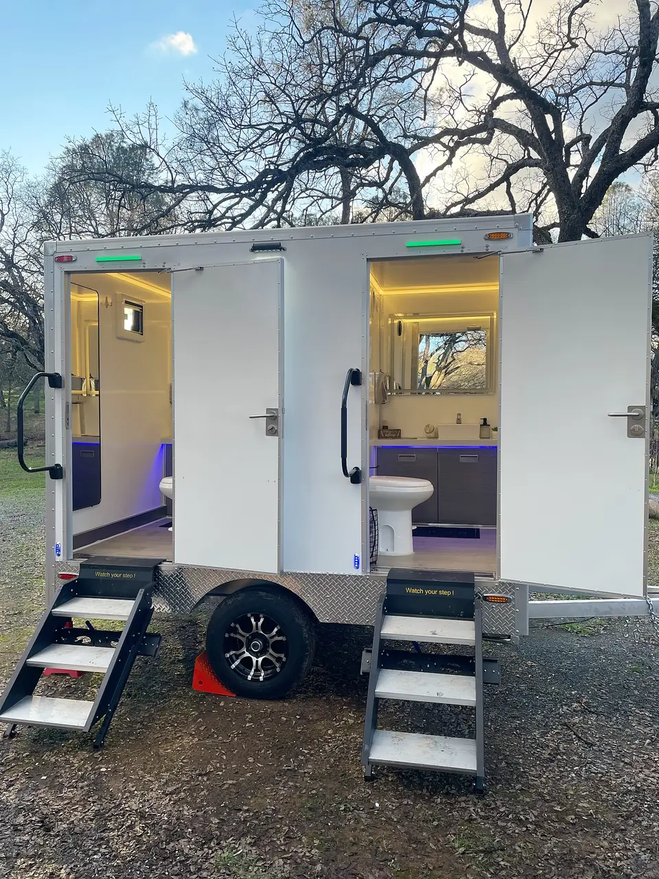 Restroom trailer with doors open showing lit interiors