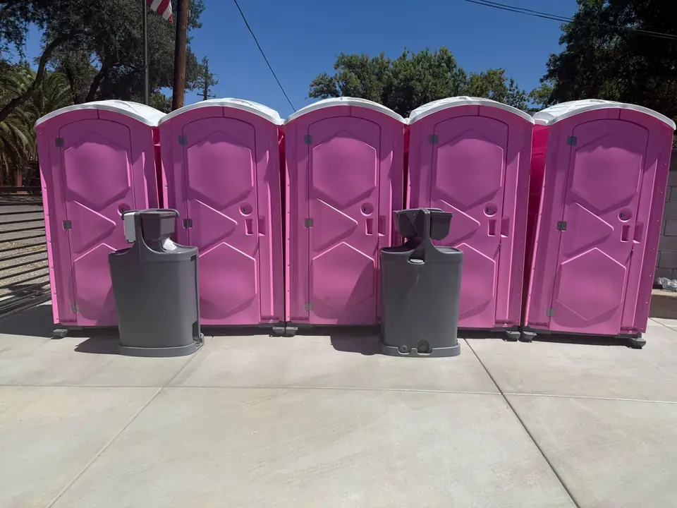 Row of pink portable toilets with two hand washing stations