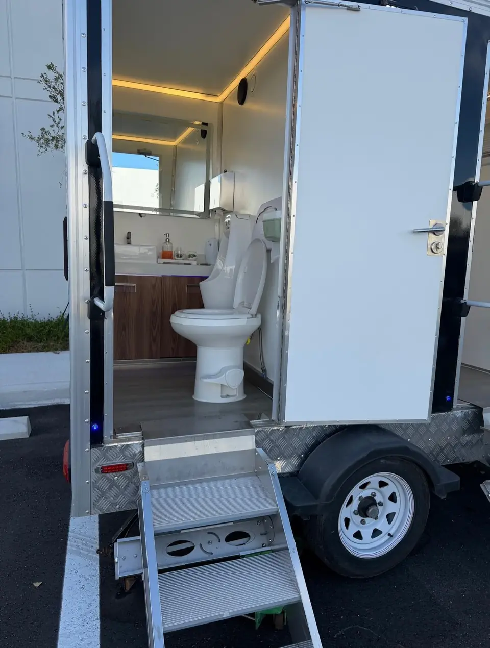 Restroom trailer stall with flush toilet and wood vanity