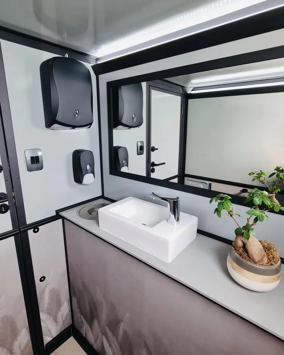 Restroom trailer interior with mirror, vessel sink and dispensers