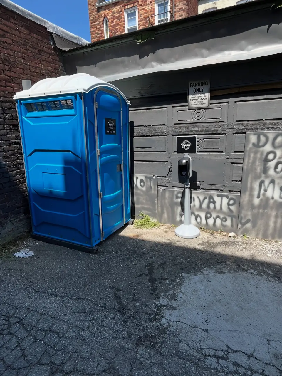 Blue standard porta potty on a paved lot